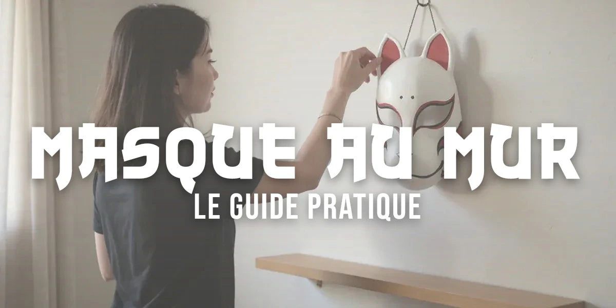 Femme accrochant un masque kitsune blanc Ă motifs rouges sur un mur clair