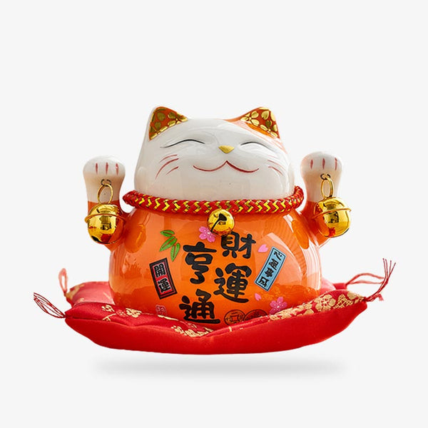 un porte bonheur chat japonais de couleurt blanche et orange avec des kanji japonais peints sur la céramiques. Le Maneki Neko a les deux pates levées en signe de chance