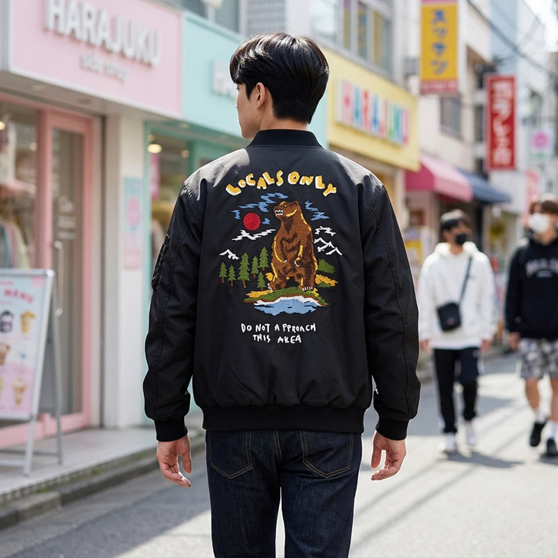 Personne portant un blouson sukajan noir orné d'un ours brodé et de caractères japonais dans une ambiance urbaine
