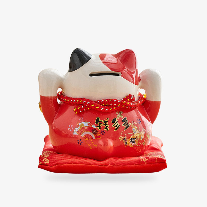 Chat Maneki Neko tirelire est de couleur rouge avec les deux pattes levées. C'est un chat porte bonheur qui favorise la bonne fortune. Il s'utilise comme une tirelire ou on dépose des pièces