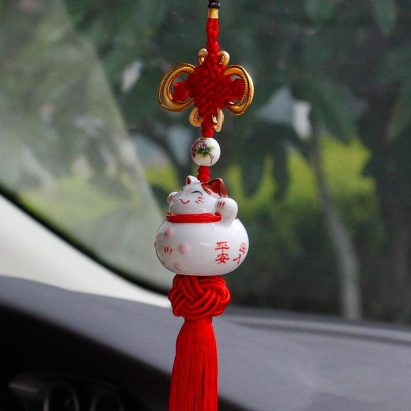 Ce chat porte-bonheur voiture un chat japonais blanc. Le chat attire la chance et c'est un objet dedecoration japonaise suspendu à des fils rouges