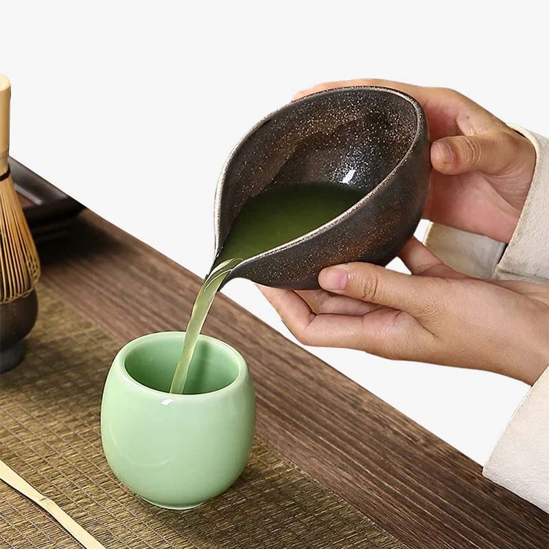 Une femme sert du thé dans une tasse blanche grâce à un bol à matcha japonais en céramique, idéal pour sublimer le rituel du thé