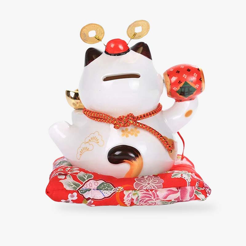 Le chat porte-bonheur Lucky Maneki Neko posé sur un coussin décoratif