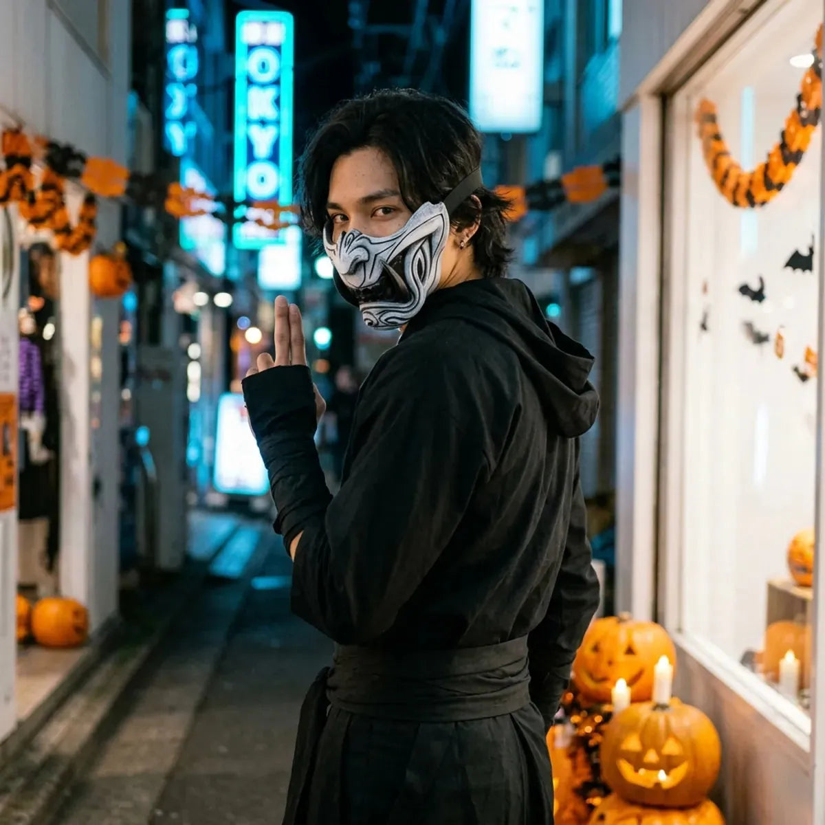 Masque menpo d'Halloween porté avec une tenue de ninja noire, regard par-dessus l'épaule dans une rue de Tokyo déserte