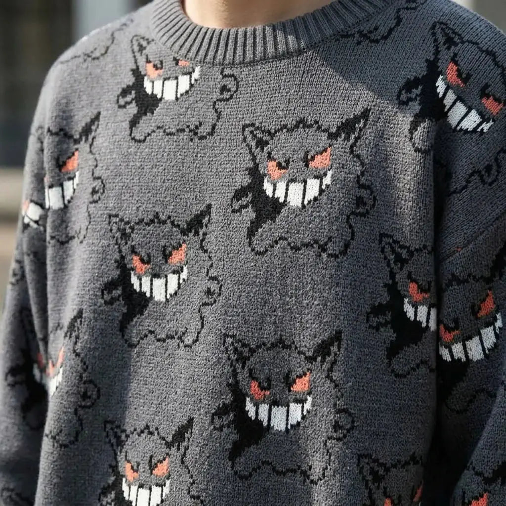 Vue rapprochée du tricot jacquard montrant des visages de fantôme aux contours noirs, avec joues roses et détail de langue rose.