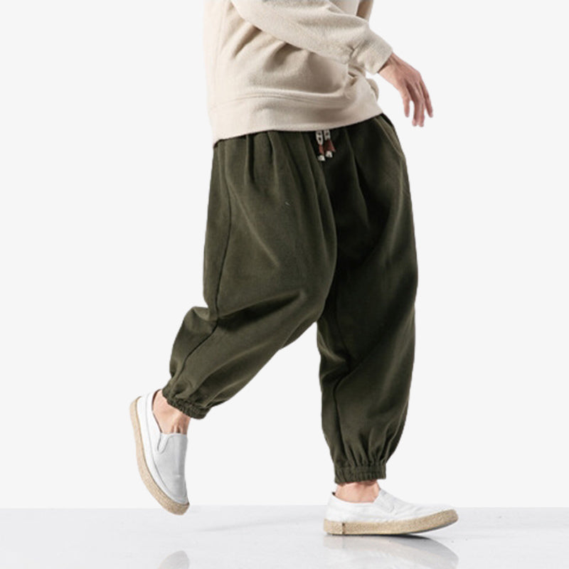 Un homme marche avec un pantalon cargot style japonais de couleur marron et unie. Pantalon japonais de qualité au style minimaliste