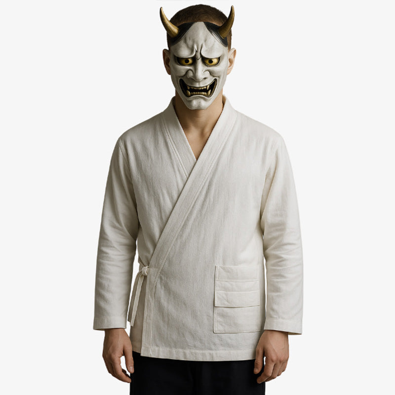 Un homme est vêtu d' un samue japonais homme de couleur blanche aux lignes épurées et au tissu respirant, qui rappelle la tenue traditionnelle des moines ou des artisans. Il dissimule son visage derrière un masque japonais traditionnel