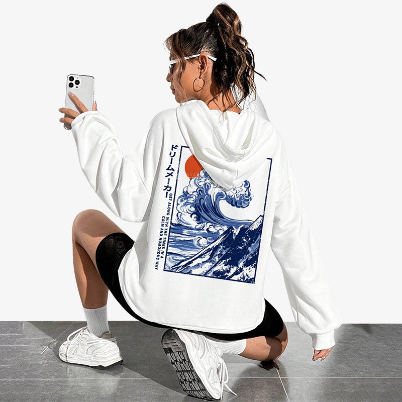 Une femme porte un Sweat okusai de couleur blanche avec un design inspiré de l emblématique Grande Vague de Knagawa, imprimée avec finesse dans le dos.
