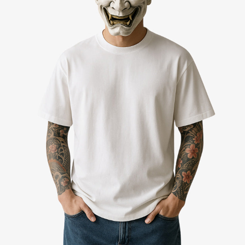 Un homme est vêtu d' un t-shirt harajuku lover. Son visage est dissimulé par un masque traditionnel hannya. Il porte des tatouages irezumi sur les bras.