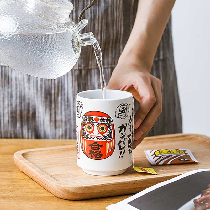 Une femme sert du the dans Une tasse style japonais daruma