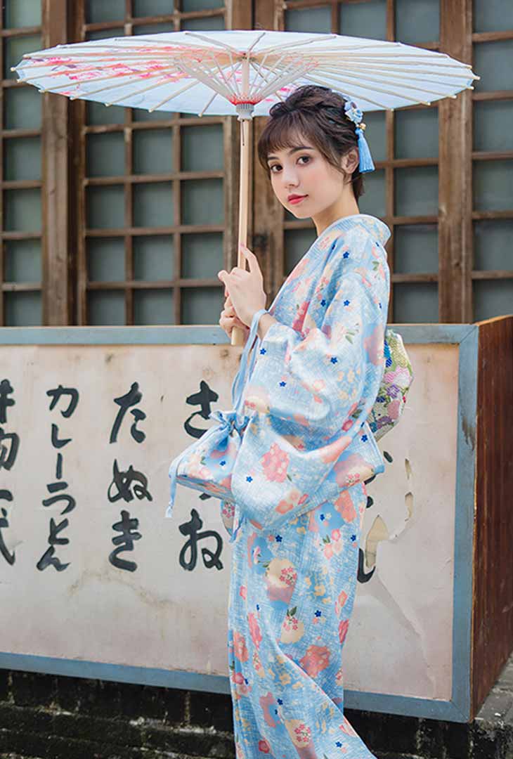 Robe kimono traditionnelle imprimée de motifs floraux japonais, la femme tient élégamment un wagasa, révélant des motifs délicats