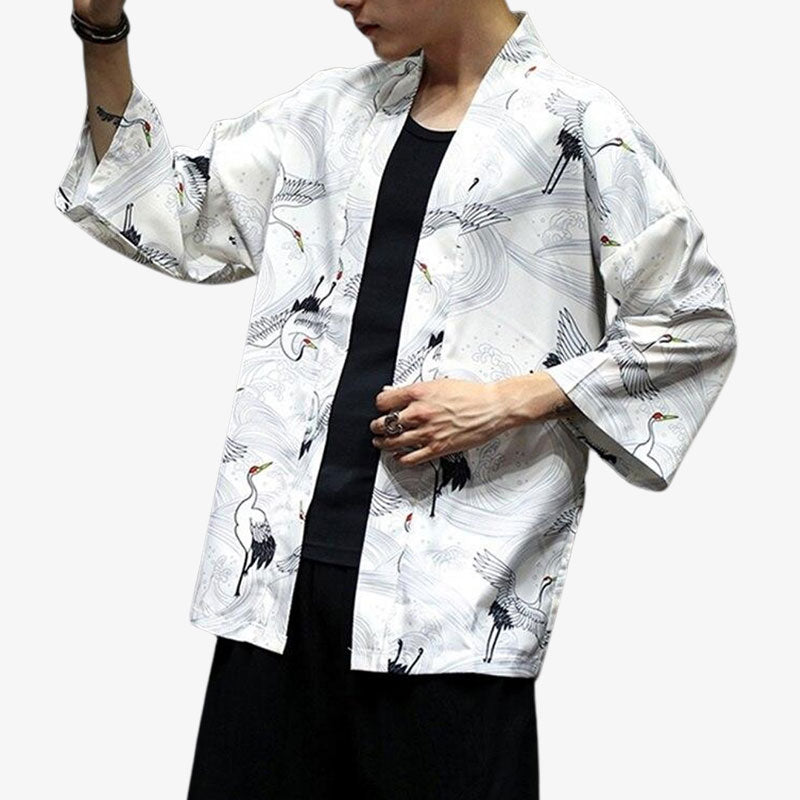 Un homme japonais est habillé avec une veste effet kimono blanc. Des motifs de grues Tsuru sont imprimés sur le tissu en coton et polyester de la veste haori kimono