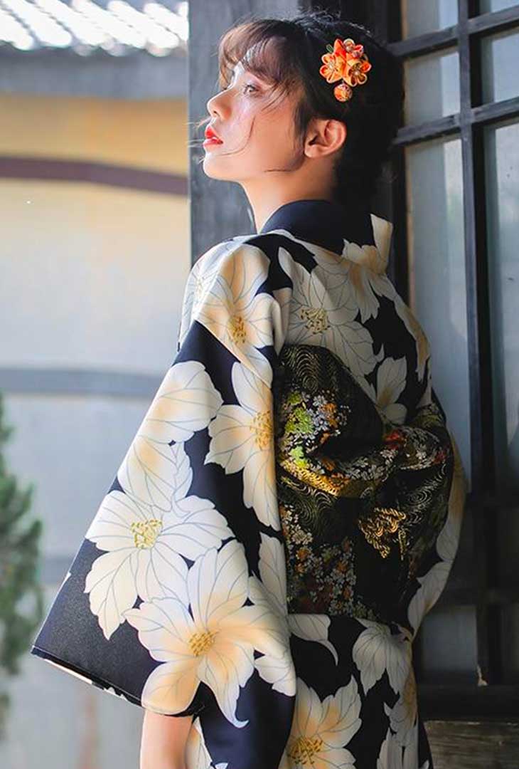Une femme est habillée avec un yukata kimono de geisha. Le tissu du kimono japonais à fleur est ceinturé avec un obi japonais