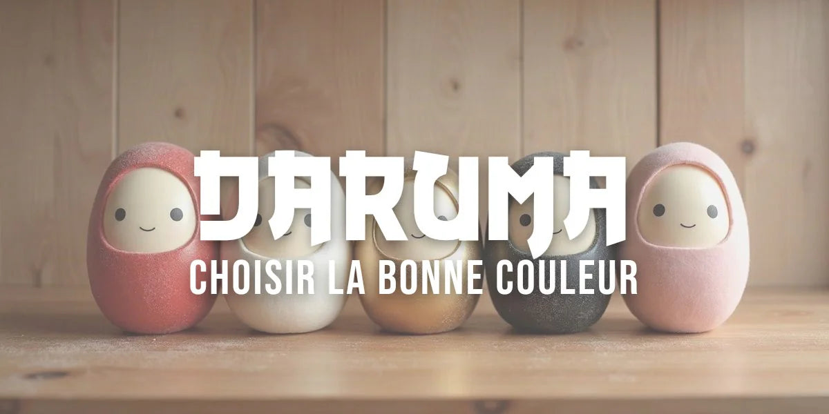 Cinq darumas de couleurs différentes arrangés sur une étagère en bois dans la lumière du jour.