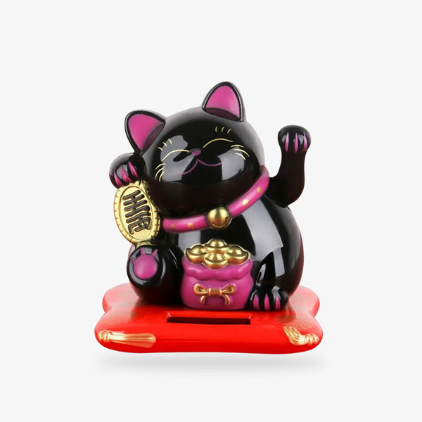 Ce chat Maneki Neko Noir est un porte-bonheur japonais. Le chat noir tient dans la main une pièce Koban. Il a un collier rose et un sac de pièce. La patte gauche du chat porte-bonheur est levée pour la bonne fortune et la chance