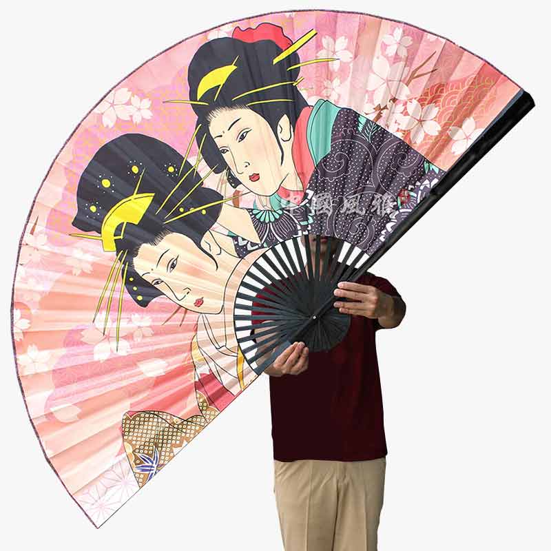 Décorez une pièce avec ce Grand Eventail Mural Japonais. Deux femmes geisha sont dessinés sur l'eventail. Il  a ayssu des fleurs de cerisiers japonais Sakura