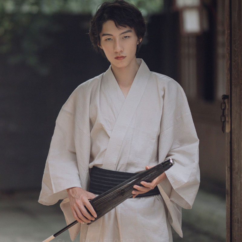 Un japonais porte un kimono blanc homme. Le yukata est attaché avec une ceinture Obi. Il tient dans la main une ombrelle japonaise