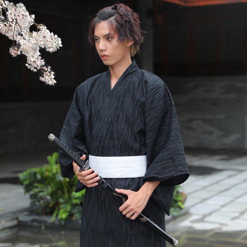 Un japonais est habillé avec un Kimono Yukata Homme. L'habit est attaché avec une ceinture Obi blanche. Ce samourai tient dans la main un sabre katana