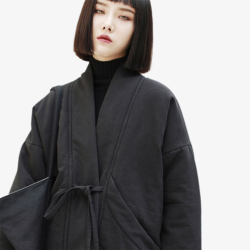 Pour un look traditionnel, une femme porte un manteau japonais en coton de couleur noir avec une ceinture finie pour fermer sa veste kimono
