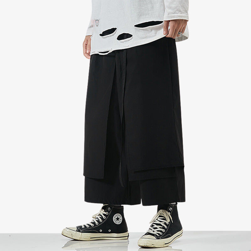 Un homme est habillé avec un pantalon japonais hakama de couleur noir et des sneakers noires