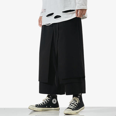 Un homme est habillé avec un pantalon japonais hakama de couleur noir et des sneakers noires