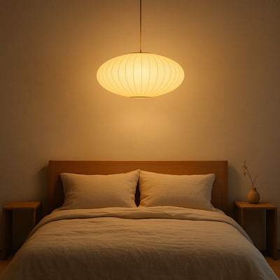 Chambre avec tête de lit en bois, deux oreillers et une suspension en soie japonaise diffusant une lumière chaleureuse