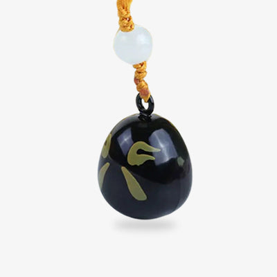 Amulette japonaise noire ornée d'un motif Daruma, symbole de protection