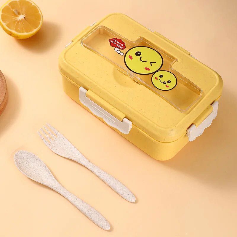 Une boite japonaise bento kawaii de couleur jaune avec un smiley sur le top du couvercle. Bento plastique fourni avec des couverts pour enfants