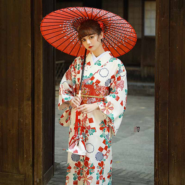 Une geisha du Japon est habillée avec un kimono japonais femme. Le vêtement est attaché avec une ceinture japonaise rouge. La matière en coton est un tissu brodé de motifs en fleurs japonaises