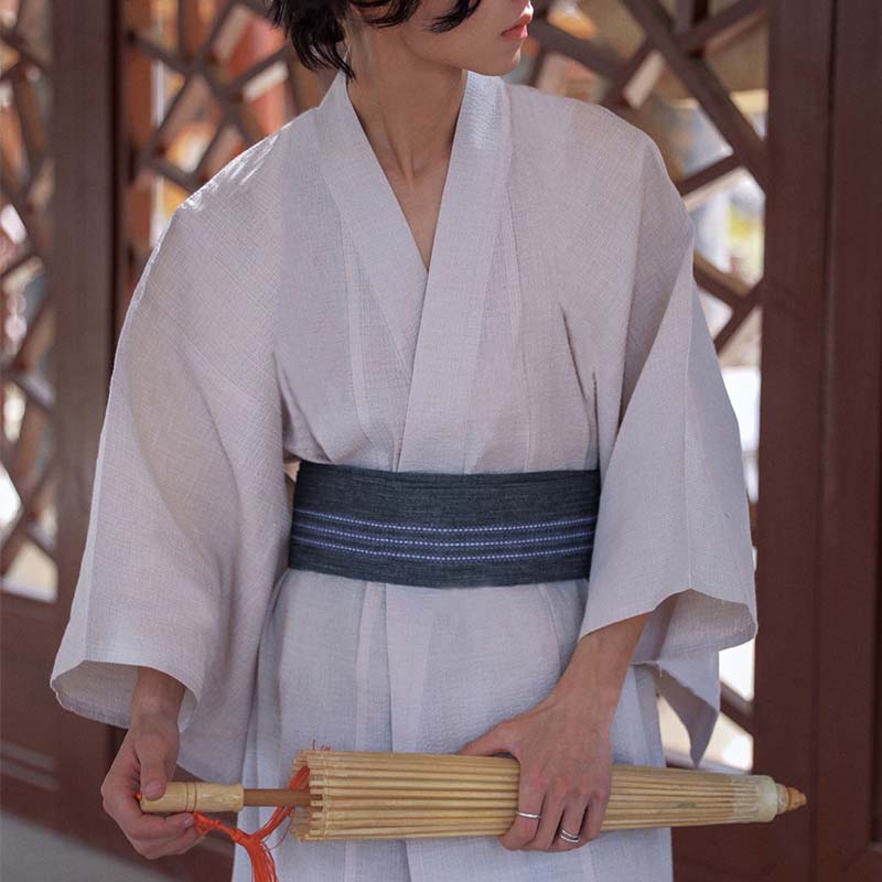 Un japonais est vêtue d'une ceinture kimono obi homme. Le yukata est de couleur blanche. Il tient dans la main une ombrelle japonaise en bambou