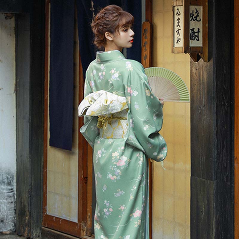 Une femme est vêtue d'une ceinture traditionnelle japonaise et d'un kimono de geisha avec des motifs floraux