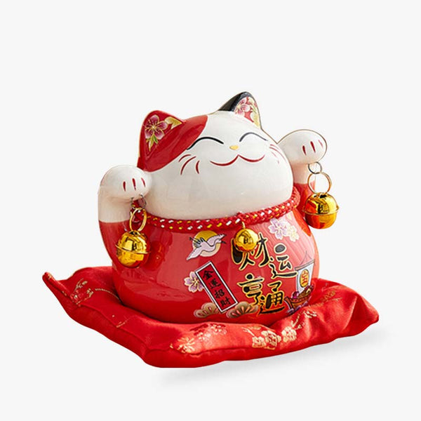 Ce chat japonais porte bonheur tirelire est fabriqué en céramique. Il est de couleur rouge et tien des clochettes dorées dans chacune de ses pates levées. Il est peint avec des inscriptions Kanji et des fleurs sur ses oreilles pointues de chat Maneki Neko