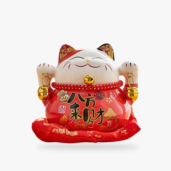 Ce Chat Maneki Neko est un porte-bonheur japonais. Il a les deux pattes levées pour attirer la chance. Ce maneki neko céramique est de couleur rouge. L'objet deco japonaise est sur un coussin rouge