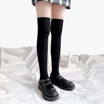 Une fille porte une paire de chaussettes hautes japonaises avec des chaussures d'écolière et une jupe à carreaux.