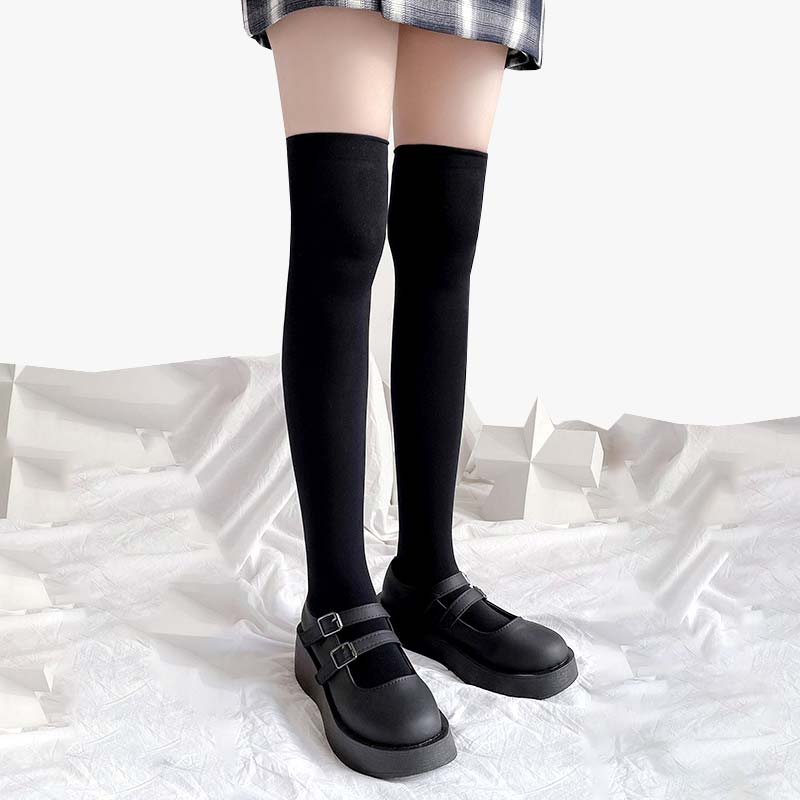 Une fille porte une paire de chaussettes hautes japonaises avec des chaussures d'écolière et une jupe à carreaux.