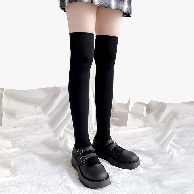 Une fille porte une paire de chaussettes japoniases hautes avec des souliers d'écolière et une jupe à carreaux