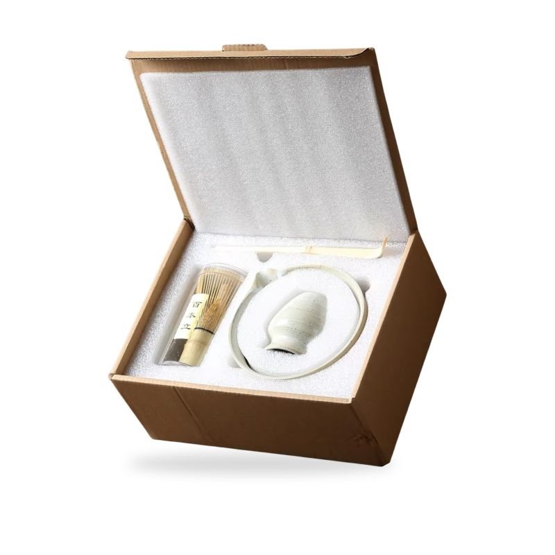 Coffret cadeau japonais ouvert contenant un bol blanc en céramique et un fouet à matcha
