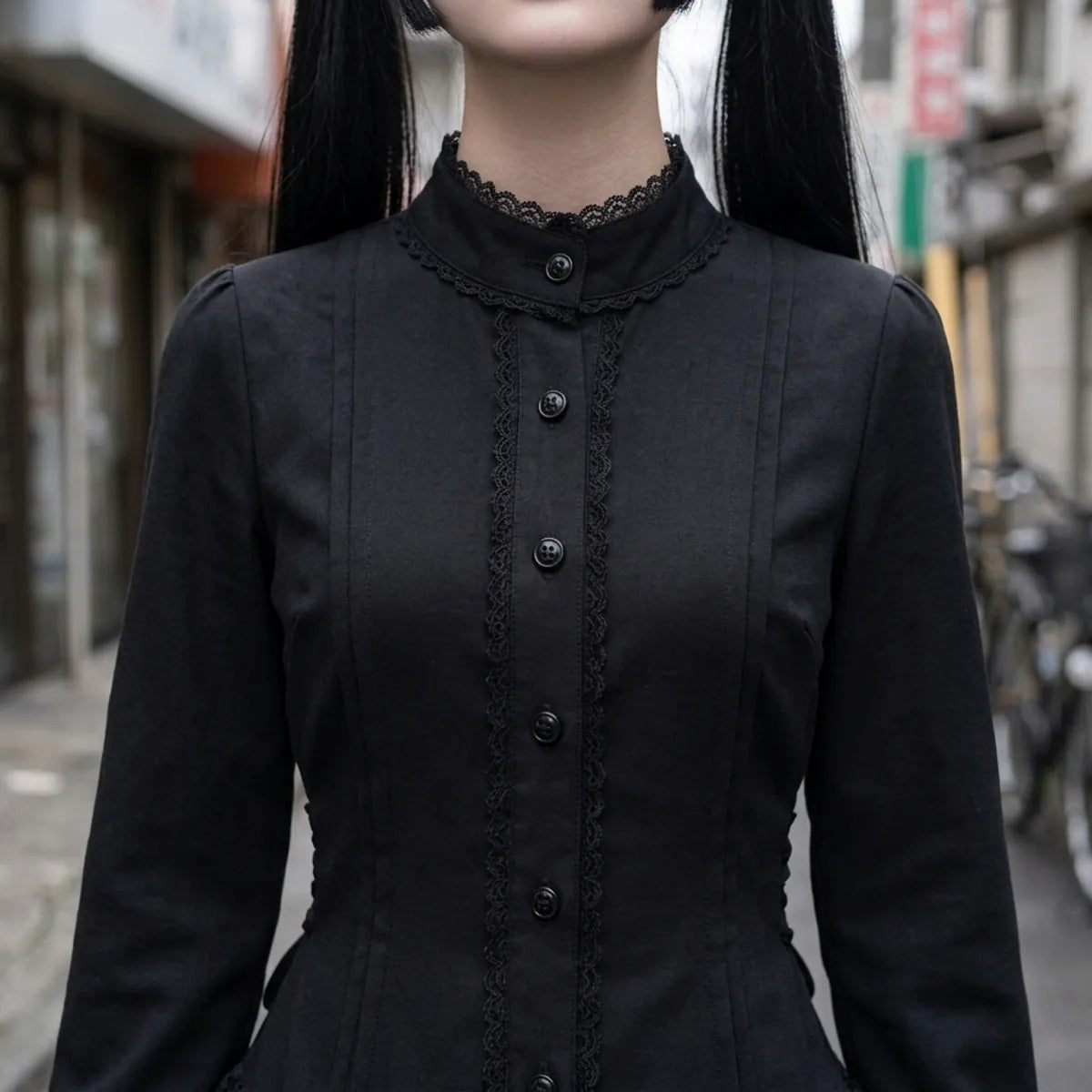 Vue rapprochée du col montant, avec la bordure en dentelle noire et la rangée de boutons sur le corsage.