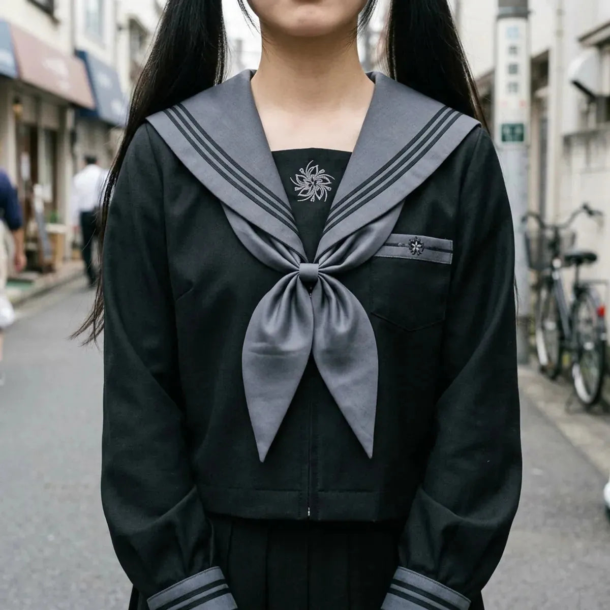 Vue rapprochée du col sailor gris à rayures noires, du foulard gris et de l'emblème brodé