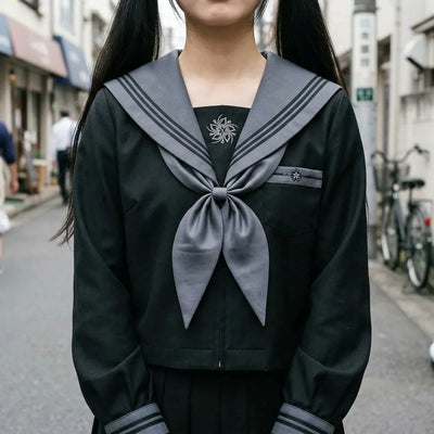 Vue rapprochée du col sailor gris à rayures noires, du foulard gris et de l'emblème brodé