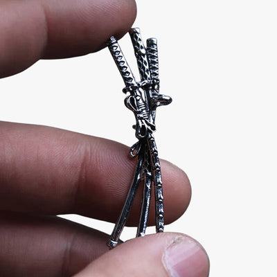 Un homme tient entre ses doigts un collier avec un katana en argent