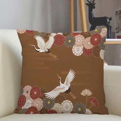 Un coussin japonais rouge posé sur un canapé de couleur beige. Des motifs de grues japonaise Tsuru sont imprimés sur le tissu coton du de la housse