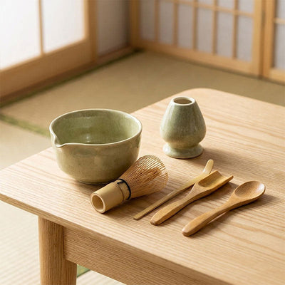 Kit matcha vert avec ustensiles en bambou sur une table en bois devant des portes coulissantes