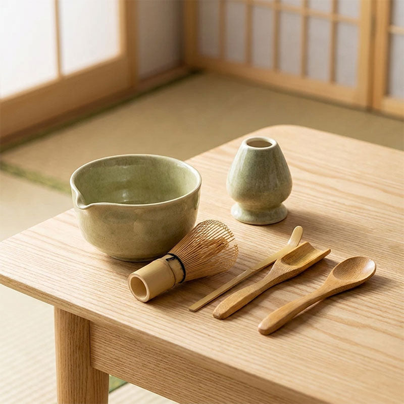 Kit matcha vert avec ustensiles en bambou sur une table en bois devant des portes coulissantes