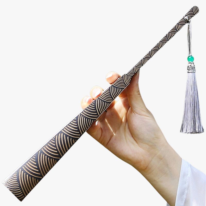 Une femme tient dans la main un éventail japonais ancien replié. L'accessoire japonais est décoré avec le motif seigaha