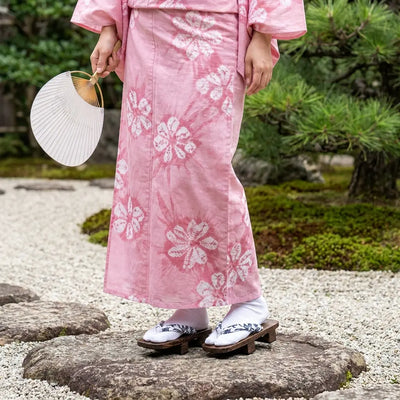 Sandales geta portées avec un kimono rose dans un jardin japonais