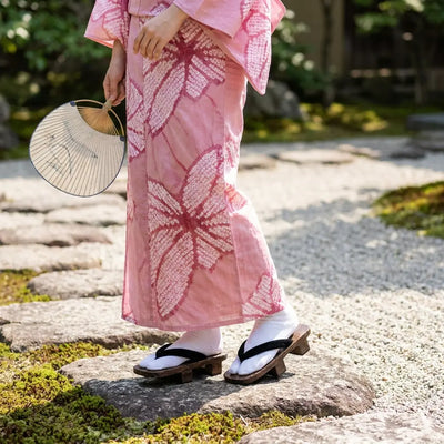 Geta Hanao Noir portées avec un kimono rose dans un jardin japonais