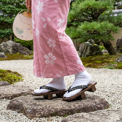 Geta portées avec un kimono rose dans un jardin japonais