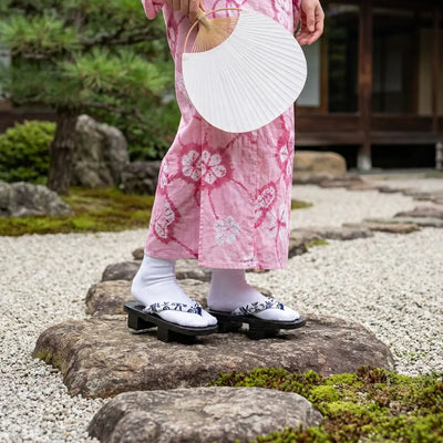 Geta en bois portée avec un kimono rose dans un jardin japonais