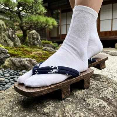 Gros plan sur la lanière bleu marine à caractères blancs des geta motif kanji